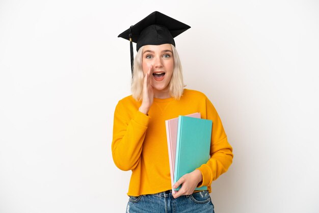 Junge kaukasische Hochschulabsolventin lokalisiert auf weißem Hintergrund, die mit weit offenem Mund schreit