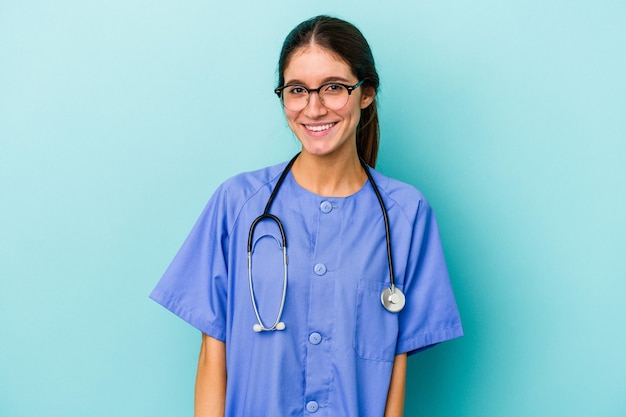 Junge kaukasische Krankenschwester isoliert auf blauem Hintergrund glücklich, lächelnd und fröhlich.