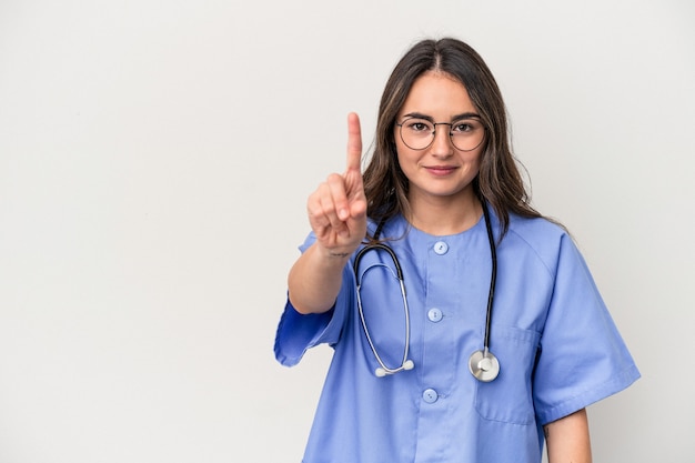 Junge kaukasische Krankenschwesterfrau lokalisiert auf weißem Hintergrund, der Nummer eins mit dem Finger zeigt.
