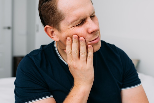 Foto junge kaukasische männliche grimassen von starken zahnschmerzen.