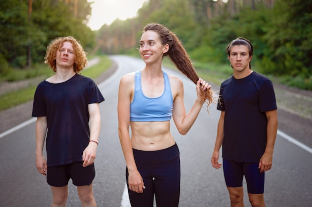 Junge kaukasische Mann- und Frauengruppe, die Asphaltstraße steht Sonniger Sommermorgen