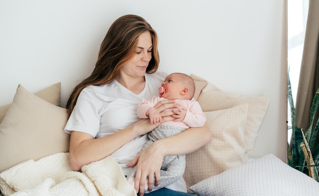 Junge kaukasische Mutter mit einem einmonatigen Baby im Arm