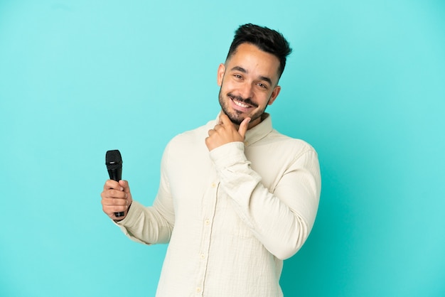 Junge kaukasische Sänger Mann isoliert auf blauem Hintergrund glücklich und lächelnd