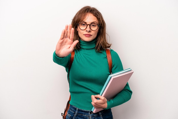 Foto junge kaukasische studentin isoliert auf weißem hintergrund, die mit ausgestreckter hand steht und ein stoppschild zeigt, das sie verhindert