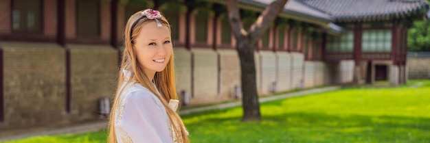 Junge kaukasische Touristin in koreanischer Hanbok-Kleidung Reise nach Korea-Konzept Nationale koreanische Kleidung Unterhaltung für Touristen, die nationale koreanische Kleidung anprobieren BANNER LANGES FORMAT