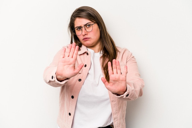 Junge kaukasische übergewichtige Frau isoliert auf weißem Hintergrund, die mit ausgestreckter Hand mit Stoppschild steht und Sie daran hindert.