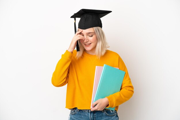 Junge kaukasische Universitätsabsolventin isoliert auf weißem Hintergrund lachend