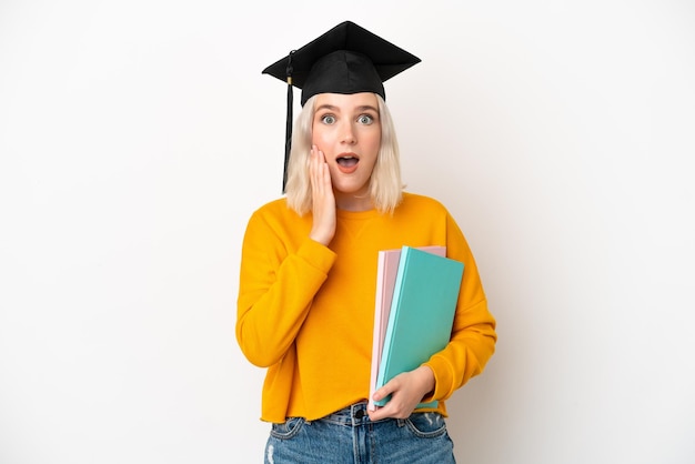 Foto junge kaukasische universitätsabsolventin isoliert auf weißem hintergrund mit überraschung und schockiertem gesichtsausdruck