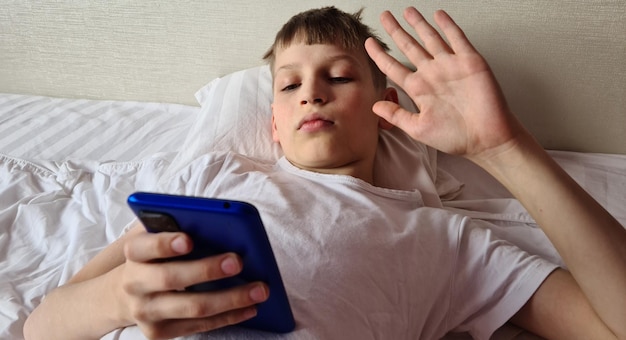 Junge Kind Teenager winkt mit der Hand auf den Smartphone-Bildschirm und spricht über Videoanruf