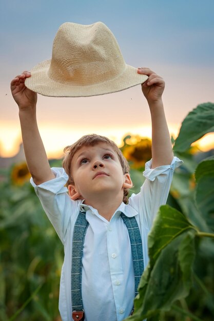 JUNGE KLEINER BAUER MIT EINEM HUT IN EINEM FELD DER SONNENBLUMEN