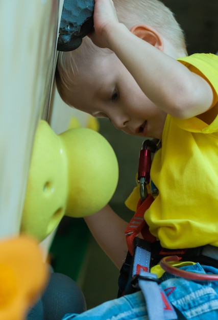 Junge klettert die Wand der Kletterwand. Aktive Erholung, Kindersport.