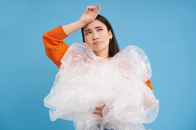 Junge Öko-Umweltaktivistin, die Plastikmüllsäcke in der Hand hält, scheint es leid zu sein, sie einzusammeln