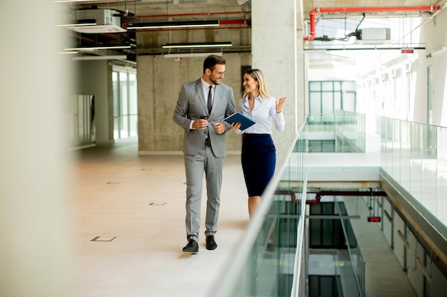 Junge Kollegen gehen und reden den Flur im modernen Büro entlang