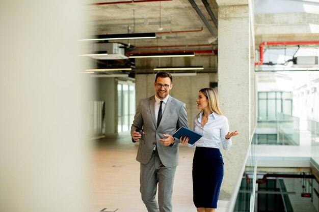 Junge Kollegen gehen und reden den Flur im modernen Büro entlang