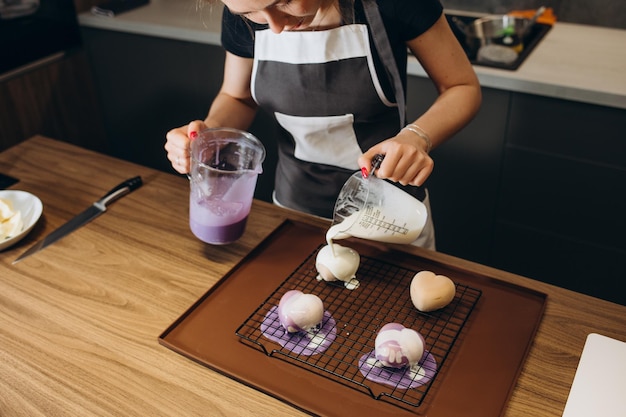 Junge Konditorin gießt flüssiges Mousse in eine Form Zubereitung von Kuchendessert in einer professionellen Küche