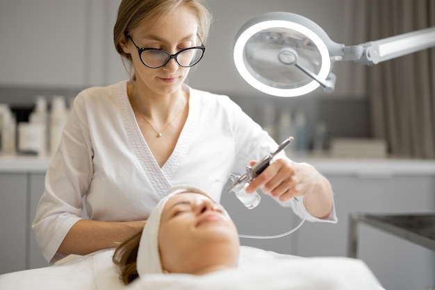 Junge Kosmetikerin führt im Schönheitssalon eine Sauerstoffmesotherapie im Gesicht einer Frau durch. Konzept einer nichtinvasiven und revitalisierenden Hautbehandlung
