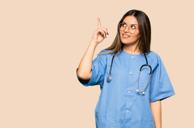 Junge Krankenschwester, die beabsichtigt, die Lösung beim Anheben eines Fingers auf lokalisiertem gelbem Hintergrund zu realisieren
