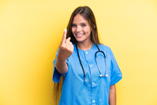 Junge Krankenschwester, kaukasische Frau isoliert auf gelbem Hintergrund, die kommende Geste macht