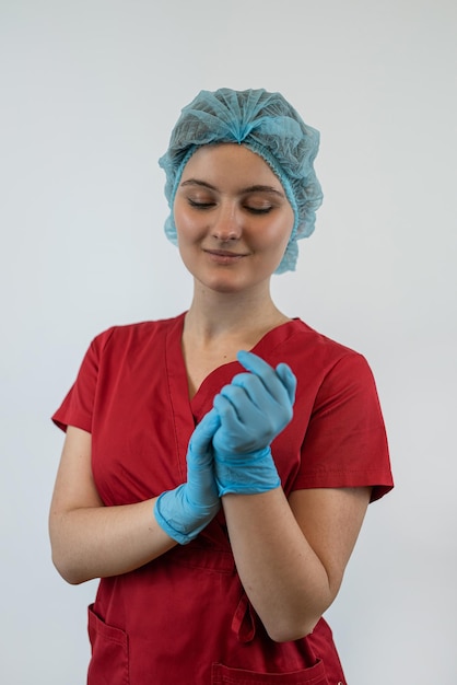Junge Krankenschwester oder Ärztin in Uniform zieht isoliert blaue Gummihandschuhe an