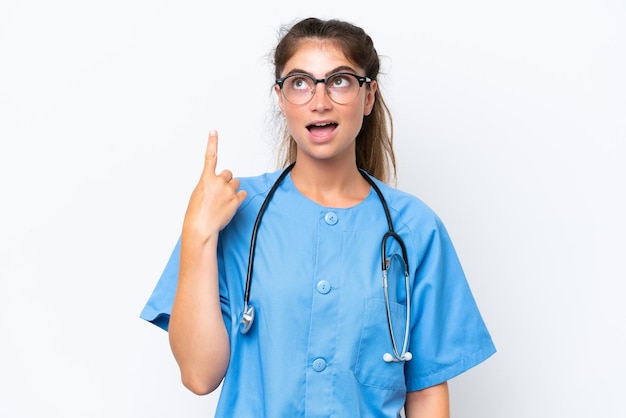 Junge Krankenschwester, Ärztin, Frau, isoliert auf weißem Hintergrund, denkt an eine Idee und zeigt mit dem Finger nach oben