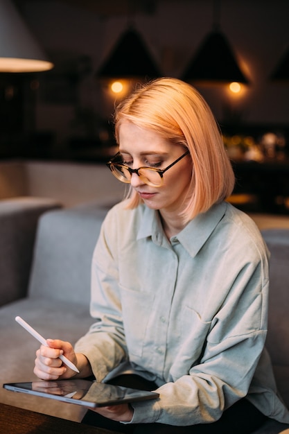 Junge kreative Designerfrau in den Gläsern, die Stift halten