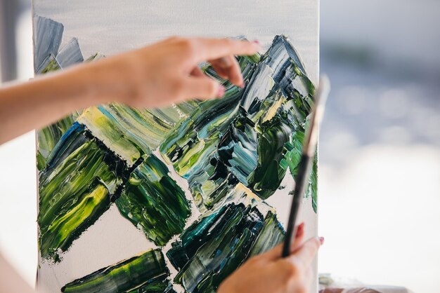Junge Künstlerin malt mit einem Spachtel auf der Leinwand