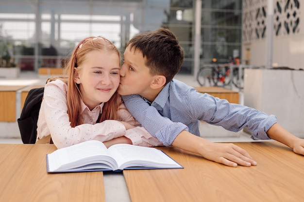 Junge küsst Mädchen im Schulhof. Das Konzept der ersten Schulliebe