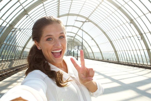 Junge lachende Frau, die selfie mit Friedenszeichen nimmt