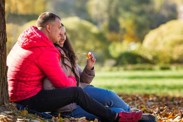 Junge lachende Mann und Frau umarmen sich im Herbstpark. Romantisches Paar bei einem Date. Liebe und Zärtlichkeit in einer Beziehung. Nahaufnahme.