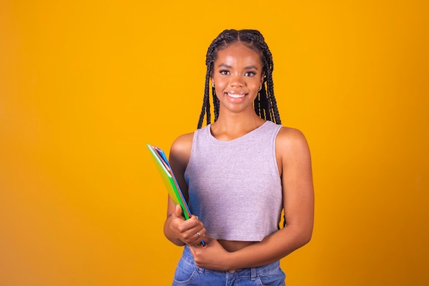 Junge lächelnde Afro-Mädchen, glücklicher Teenager-Student, der Bücher und Notizbücher im Hintergrund mit freiem Platz für Text hält