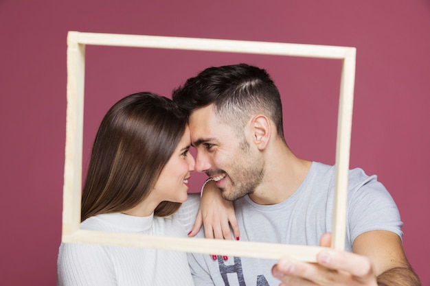 Junge lächelnde Dame mit der Hand auf der Schulter des positiven Kerls Fotorahmen zeigend