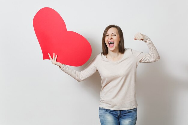 Junge lächelnde Frau des hübschen Spaßes, die großes rotes Herz in den Händen lokalisiert auf weißem Hintergrund hält. Kopieren Sie Platz für Werbung. Mit Platz für Text. Valentinstag- oder Internationaler Frauentag-Konzept.