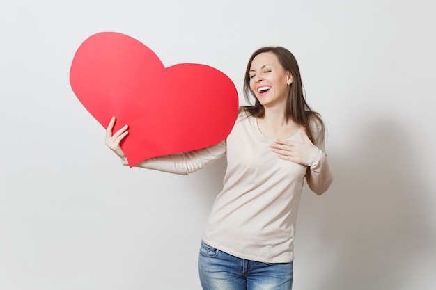 Junge lächelnde Frau des hübschen Spaßes, die großes rotes Herz in den Händen lokalisiert auf weißem Hintergrund hält. Kopieren Sie Platz für Werbung. Mit Platz für Text. Valentinstag- oder Internationaler Frauentag-Konzept.