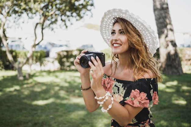Junge lächelnde Frau, die Fotos mit ihrer Digitalkamera macht, während sie einen Sommerurlaub genießt.
