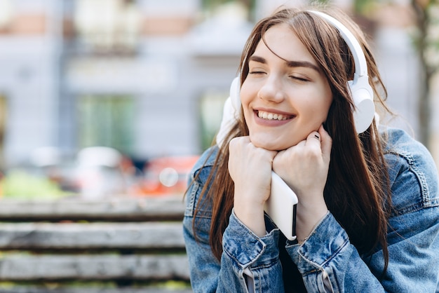 Junge, lächelnde Frau, die Musik mit Kopfhörern hört. Mädchen, das Lieder über drahtlose Kopfhörer hört. Nahaufnahmegesicht des Teenagers.