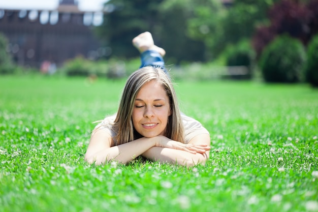 Junge lächelnde Frau, die sich auf dem Gras hinlegt