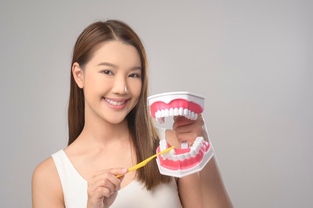 Junge lächelnde Frau, die Zahnbürste über weißem Hintergrundstudio hält