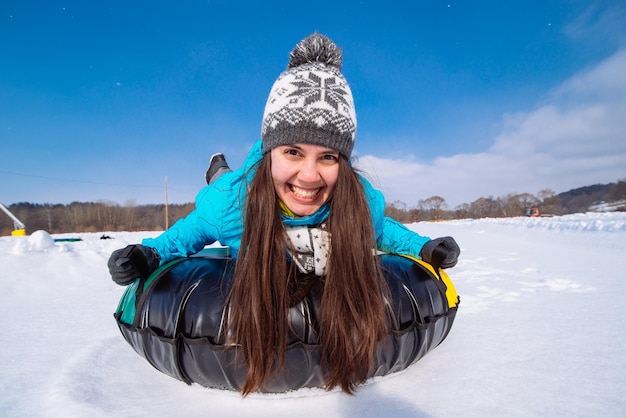 Junge lächelnde Frau hält sich für Schlitten fest. Snow-Tubing. Winteraktivitätskonzept