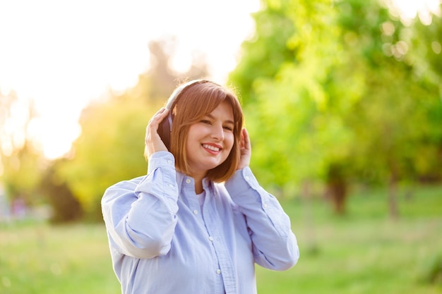Junge lächelnde Frau hört Musik mit drahtlosen schwarzen Kopfhörern bei Sonnenuntergang Mädchen hört Lieder