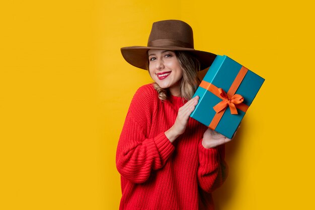 Junge lächelnde Frau in der roten Strickjacke mit Geschenkbox