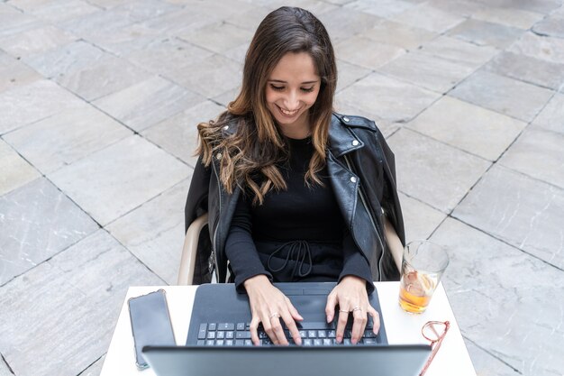 Junge lächelnde Frau mit einem Laptop am Tisch in einem Café