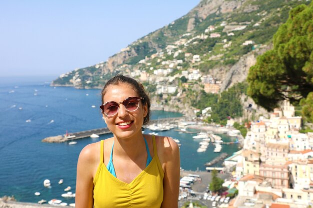 Junge lächelnde Frau mit Sonnenbrille und Amalfi-Dorf in Italien