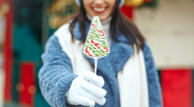 Junge lächelnde Frau mit Süßigkeiten auf dem Weihnachtsmarkt