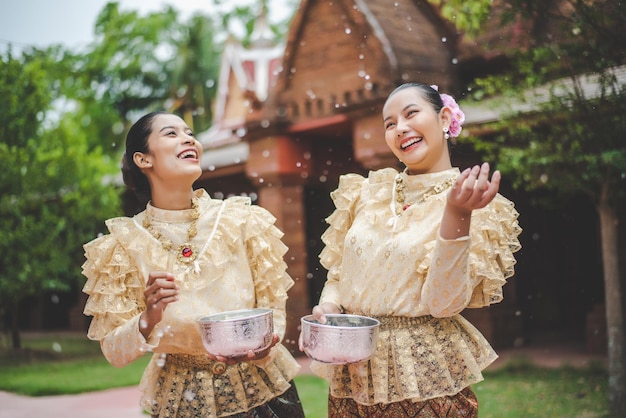 Junge lächelnde Frauen kleiden sich in wunderschönen thailändischen Kostümen, spritzen Wasser in Tempeln und bewahren die gute Kultur der Thailänder während des Songkran-Festivals am thailändischen Neujahrs-Familientag im April