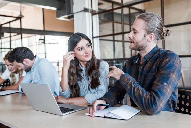 Junge lächelnde Geschäftskollegen, die im Büro sprechen und zusammenarbeiten