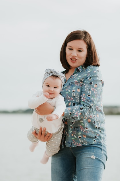 Junge lächelnde Mutter mit ihrem Baby am Strand