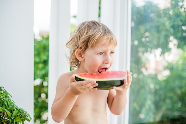 Junge lächelt und isst Wassermelone