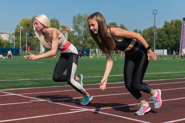 Junge Läuferin mit zwei Athleten im Stadion im Freien