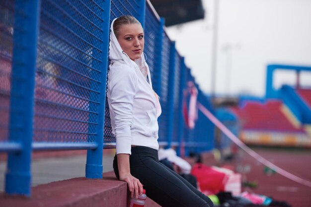 junge läuferin sportliche frau, die sich auf der athletischen rennstrecke entspannt und dehnt