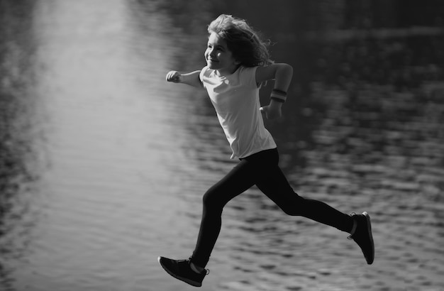 Junge läuft oder joggt in der Nähe des Sees auf Gras im Park, Outdoor-Sport und Fitness für Kinder, die Sport treiben